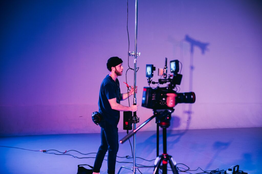 Camera operator adjusting a professional studio camera rig, illustrating how one participant can record and manage a separate video feed during a collaborative broadcast.